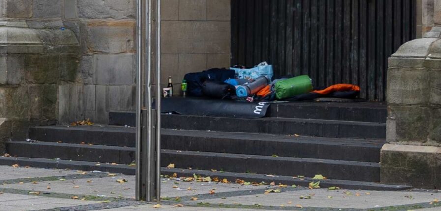 Schlafsäcke und Isomatten liegen auf einer Steintreppe vor einer Kirchentür