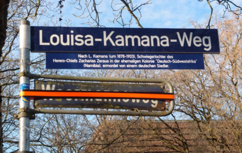 Zwei Straßenschilder, "Woermannsweg" ist mit Klebeband überklebt, darüber steht "Louisa-Kamana-Weg"