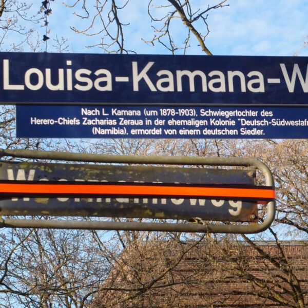 Zwei Straßenschilder, "Woermannsweg" ist mit Klebeband überklebt, darüber steht "Louisa-Kamana-Weg"