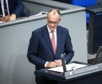 Ein Mann im dunkelblauen Anzug mit rot-weiß gemusterter Krawatte steht am Rednerpult des Bundestags