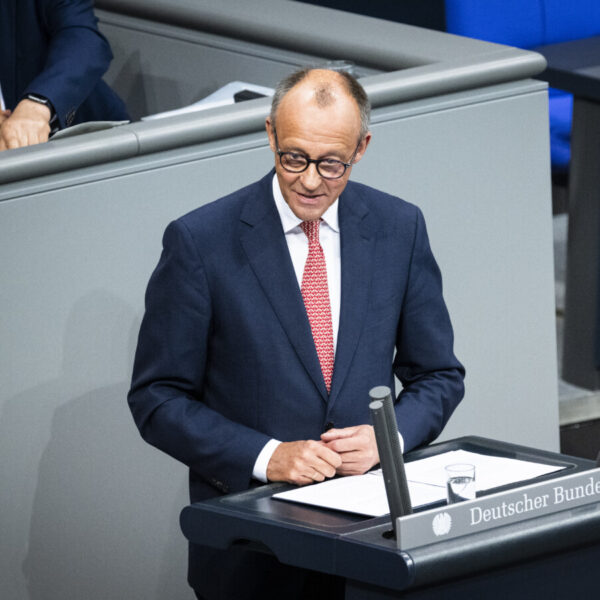 Ein Mann im dunkelblauen Anzug mit rot-weiß gemusterter Krawatte steht am Rednerpult des Bundestags