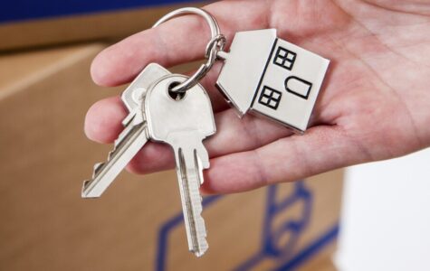 Hand hält Hausschlüsselanhänger in Hausform aus Metall