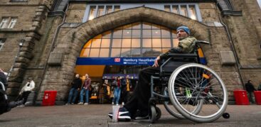 Ein Mann im Bundeswehrparka sitzt vor dem Hauptbahnhof in einem Rollstuhl