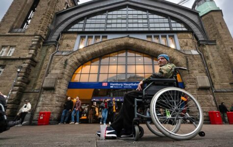 Ein Mann im Bundeswehrparka sitzt vor dem Hauptbahnhof in einem Rollstuhl