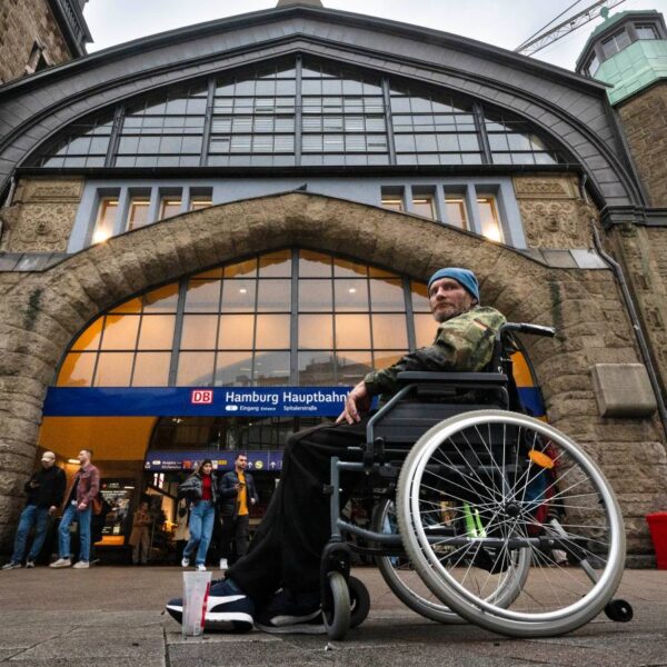 Ein Mann im Bundeswehrparka sitzt vor dem Hauptbahnhof in einem Rollstuhl