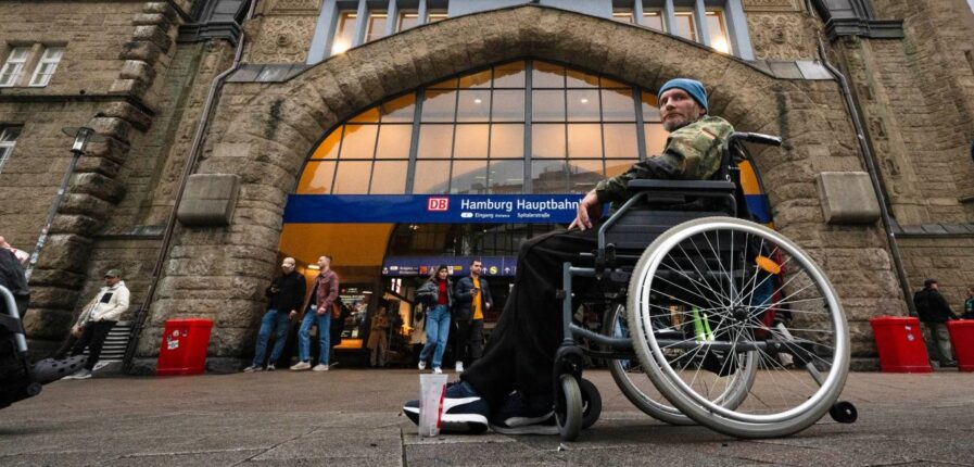 Ein Mann im Bundeswehrparka sitzt vor dem Hauptbahnhof in einem Rollstuhl