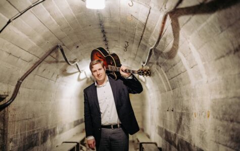 Ein Mann mit einer Gitarre auf der Schulter geht durch einen Tunnel