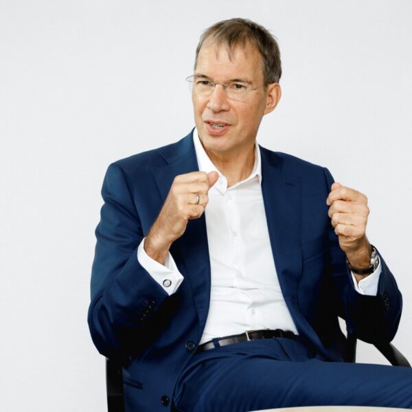 Ein Mann in dunkelblauem Anzug und weißem Hemd gestikuliert