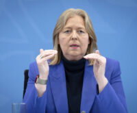 Eine blonde Frau im blauen Sakko gestikuliert