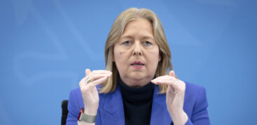 Eine blonde Frau im blauen Sakko gestikuliert