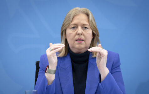 Eine blonde Frau im blauen Sakko gestikuliert