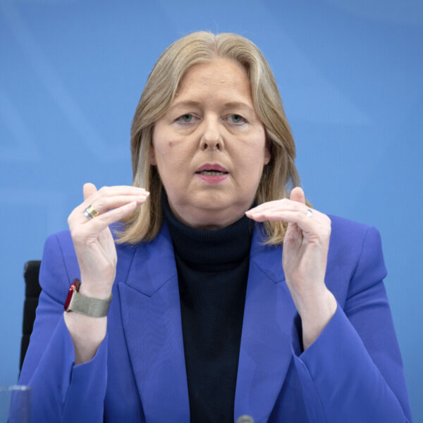 Eine blonde Frau im blauen Sakko gestikuliert