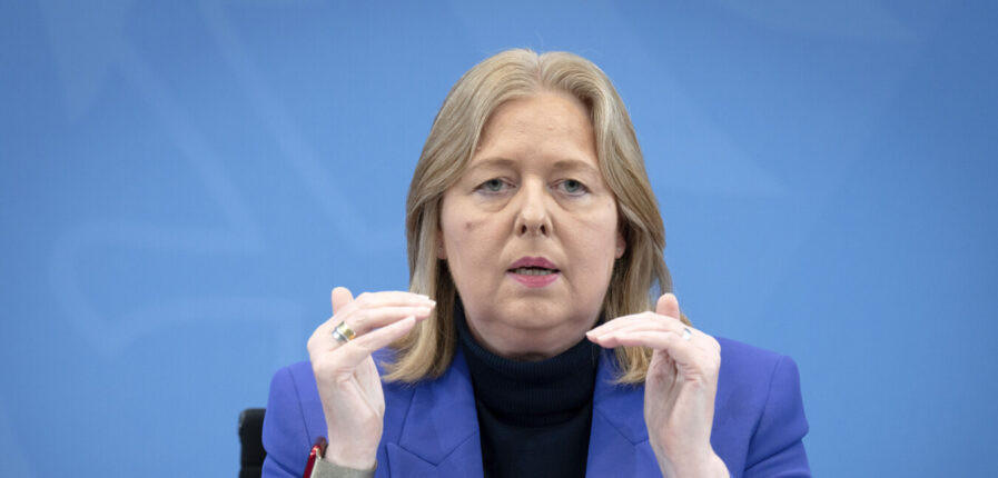 Eine blonde Frau im blauen Sakko gestikuliert