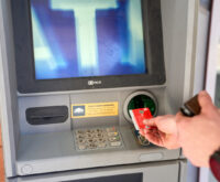 Jemand steckt eine EC-Karte in einen Geldautomaten