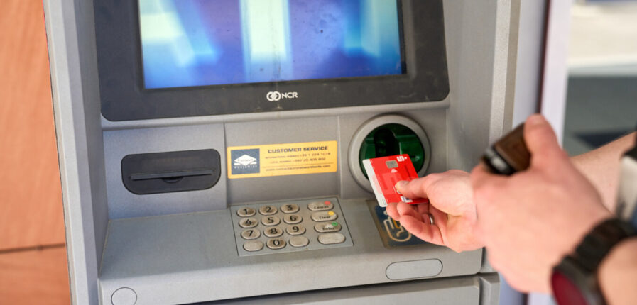 Jemand steckt eine EC-Karte in einen Geldautomaten