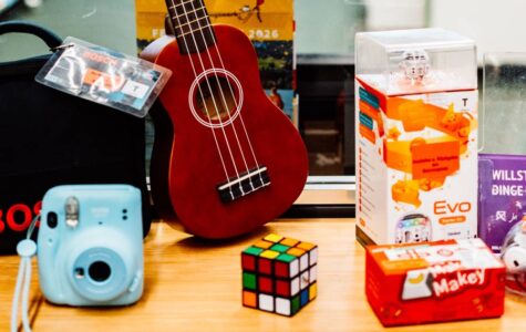 Eine Ukulele, ein Zauberwürfel und andere Dinge vor einem Schild mit der Aufschrift "Bibliothek der Dinge"