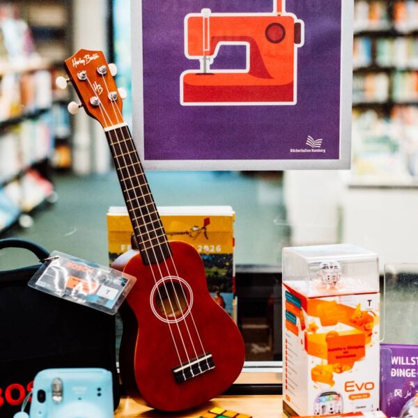 Eine Ukulele, ein Zauberwürfel und andere Dinge vor einem Schild mit der Aufschrift "Bibliothek der Dinge"