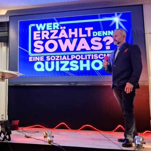 Ein großer Bildschirm mit der Aufschrift "Wer erzählt denn sowas? Eine sozialpolitische Quizshow"