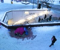 Ein Luftbild von den Treppen zur S-Bahn im Schnee, daneben Schlafsäcke