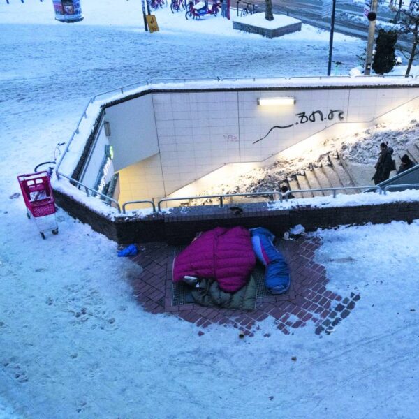 Ein Luftbild von den Treppen zur S-Bahn im Schnee, daneben Schlafsäcke