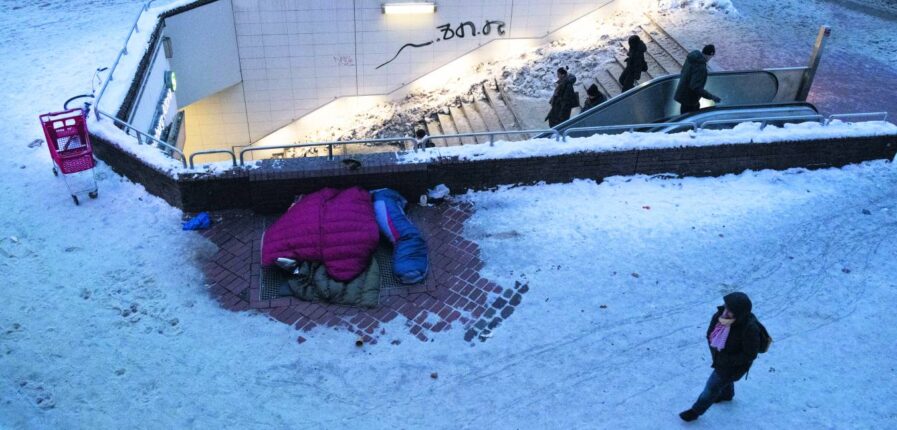 Ein Luftbild von den Treppen zur S-Bahn im Schnee, daneben Schlafsäcke