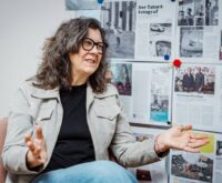 Eine Frau mit dunklen Haaren und dunkler Brille gestikuliert beim Sprechen