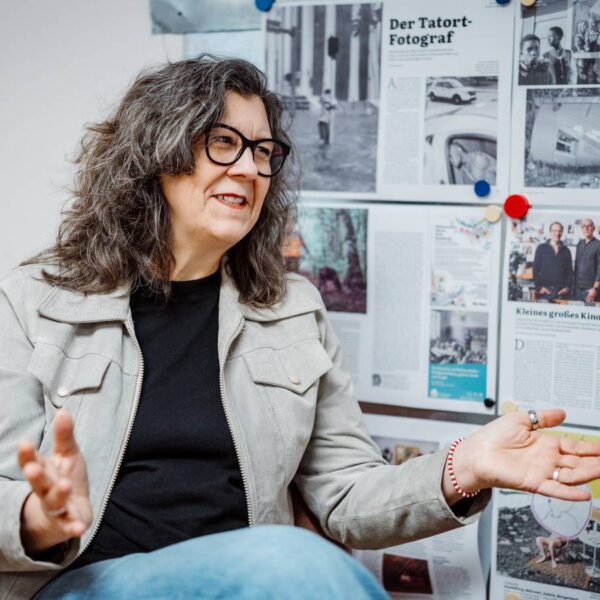 Eine Frau mit dunklen Haaren und dunkler Brille gestikuliert beim Sprechen