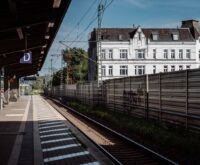 Ein weißes Haus von einem Bahnsteig aus fotografiert.