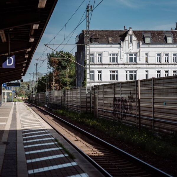 Ein weißes Haus von einem Bahnsteig aus fotografiert.