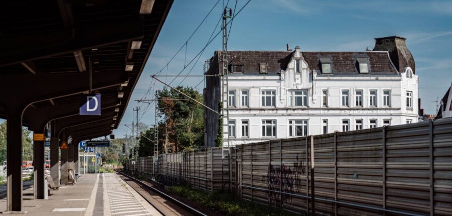 Ein weißes Haus von einem Bahnsteig aus fotografiert.