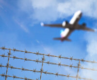 Ein Flugzeug fliegt über Stacheldraht