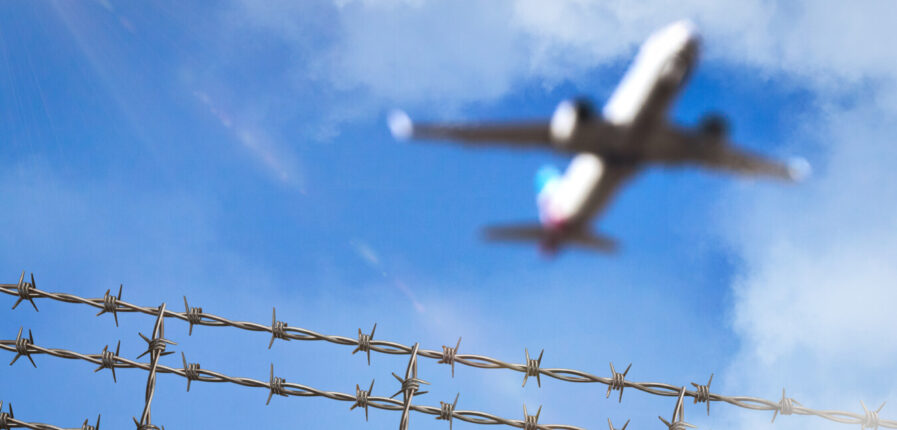 Ein Flugzeug fliegt über Stacheldraht