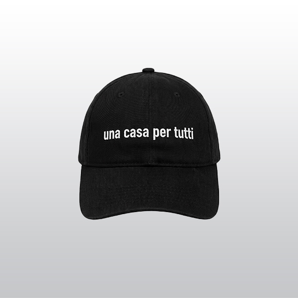 Schwarze Schirmmütze mit weißer Stickerei. Text: Una Casa per Tutti". Übersetzt: Ein Haus für alle. An der Seite ist klein der Hinz&Kunzt Schriftzug gestickt.