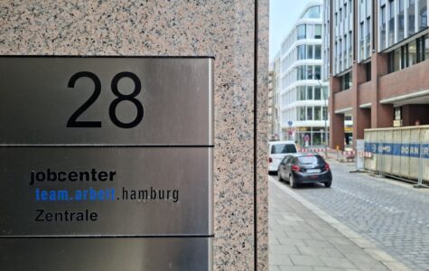 Ein Türschild mit der Aufschrift "jobcenter team.arbeit.hamburg Zentrale"