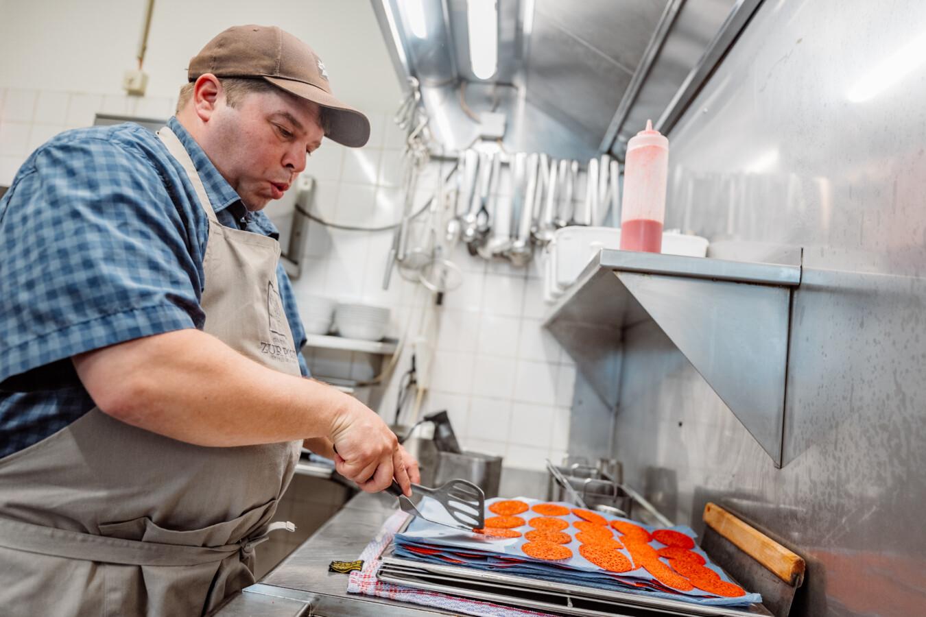 Ein Mann mit Kochschürze steht vor roten Plätzchen in einer Küche