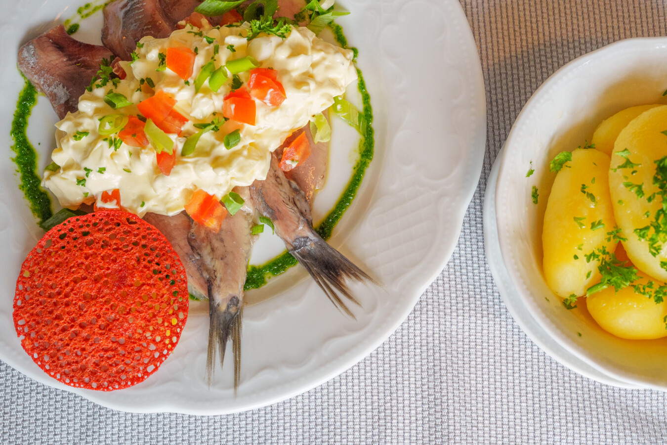 Ein Teller mit zwei Fischfilets und bunt angemachtem Kartoffelsalat
