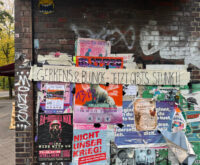 An einer Hauswand hängen viele Plakate. Quer darüber hängt ein Banner mit der Aufschrift: "Gerkens & Blunck – Jetzt gibt's Stunk"