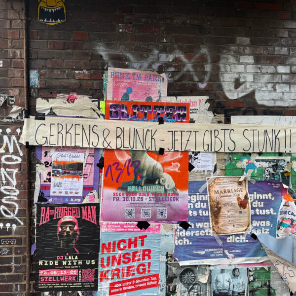 An einer Hauswand hängen viele Plakate. Quer darüber hängt ein Banner mit der Aufschrift: "Gerkens & Blunck – Jetzt gibt's Stunk"