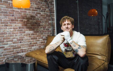 Malte Zierden sitzt auf einem beigen Sofa und lächelt freundlich in die Kamera.